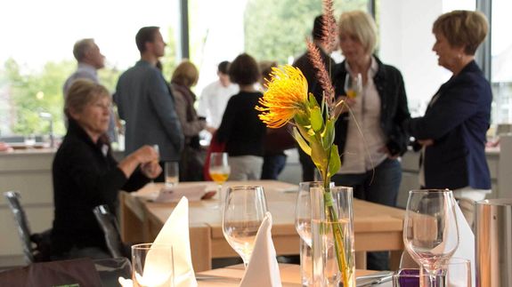 Die Gäste einer Firmenfeier genießen die Firmenfeier im Kochatelier Bergisch Gladbach und freuen sich auf das gemeinsam Essen an den eingedeckten TIschen.
