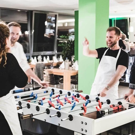 Kickertime statt Kaffeepause – Teilnehmer*innen während der Tischkicker-Challenge beim Teamworkshop im Kochatelier Köln.