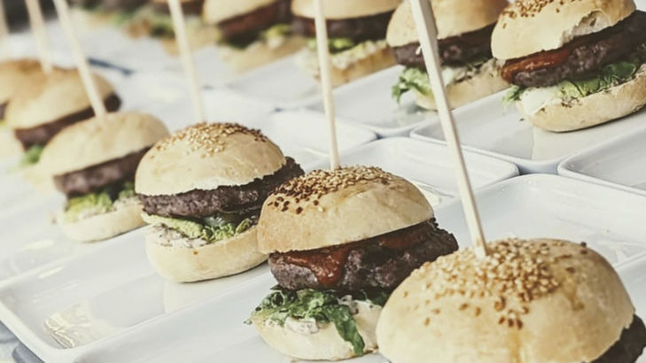 Kochateliers Burger auf Tellern mit Salat und Ketchup fertig angerichtet: Burger Buns und Pattys, alles selbst gemacht.