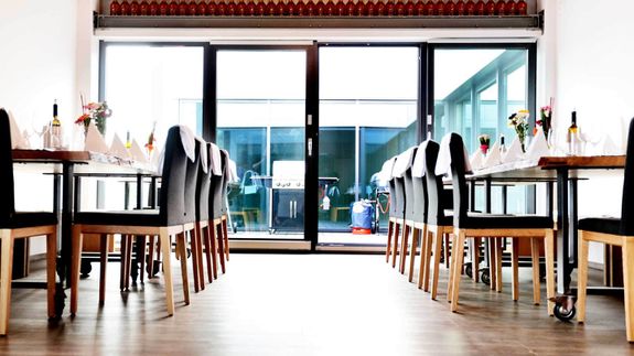 Helle großzügige Platzierung der Gäste an langen Tischen im Koch- und Grillatelier Bornheim.