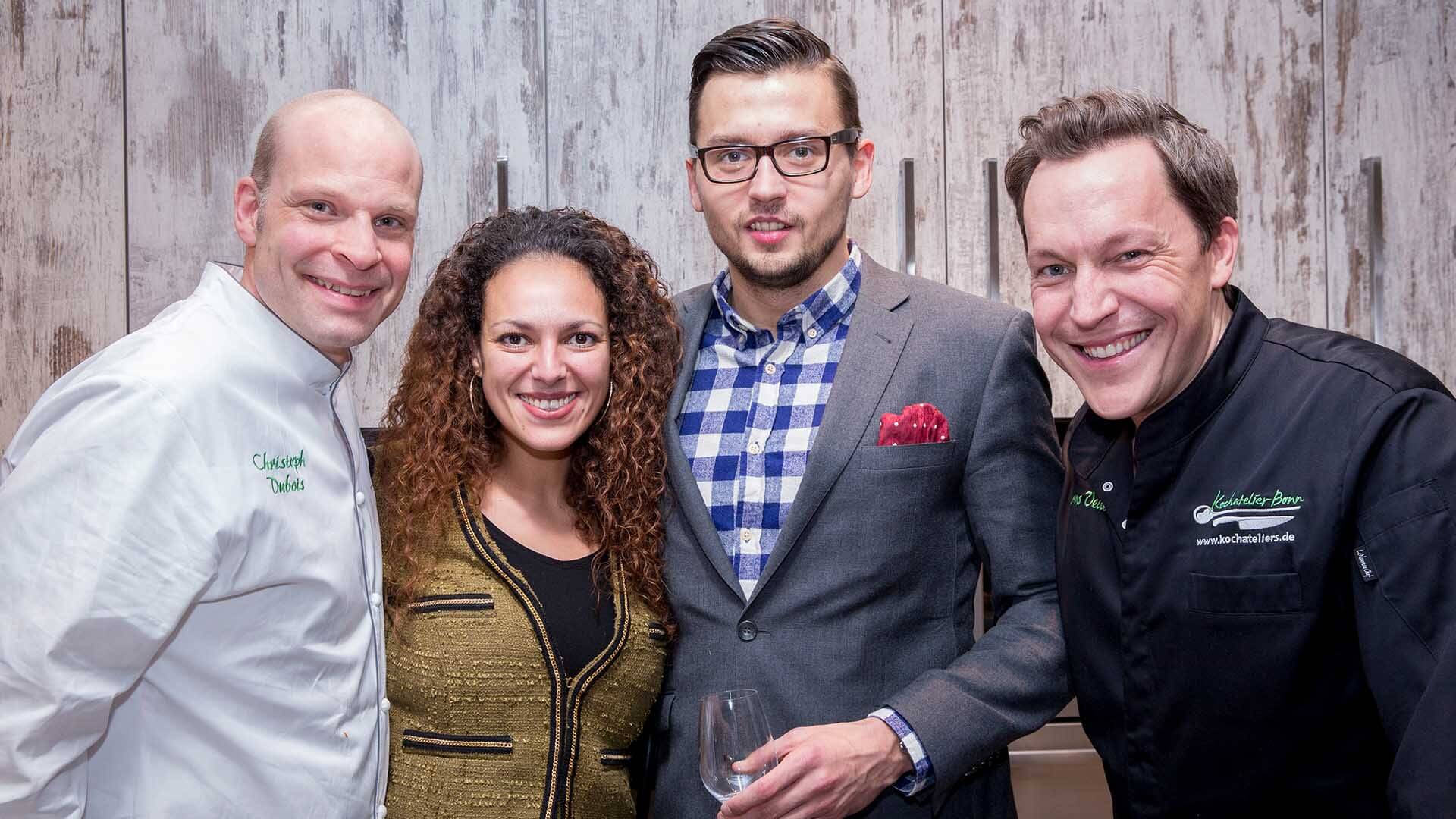 Glückliche Gastgeber und Kochateliers Küchenchêfs posieren für das Erinnerungsfoto vom gelungenen Firmenevent in Düsseldorf.